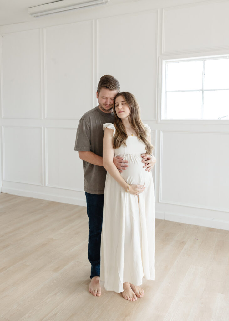 Mom and dad embracing during their Oklahoma maternity studio session, slowing down before 2nd baby arrives