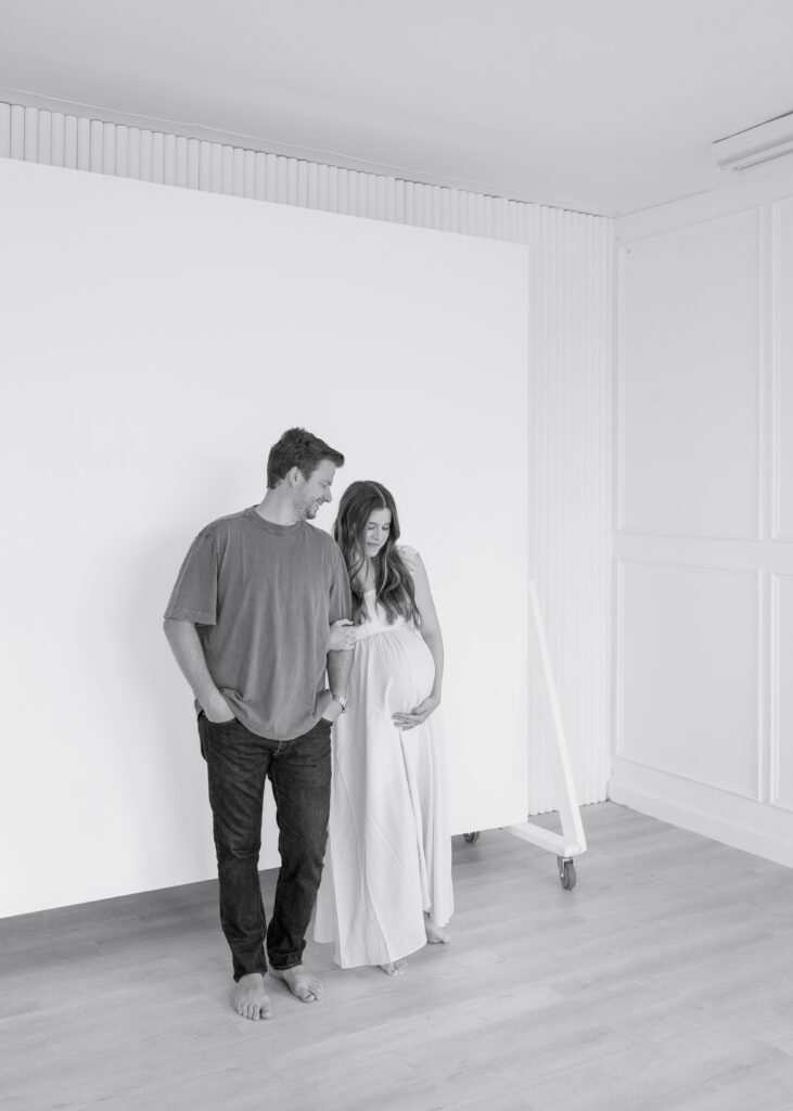 mom and dad looking down at pregnant belly before due date, denton texas maternity