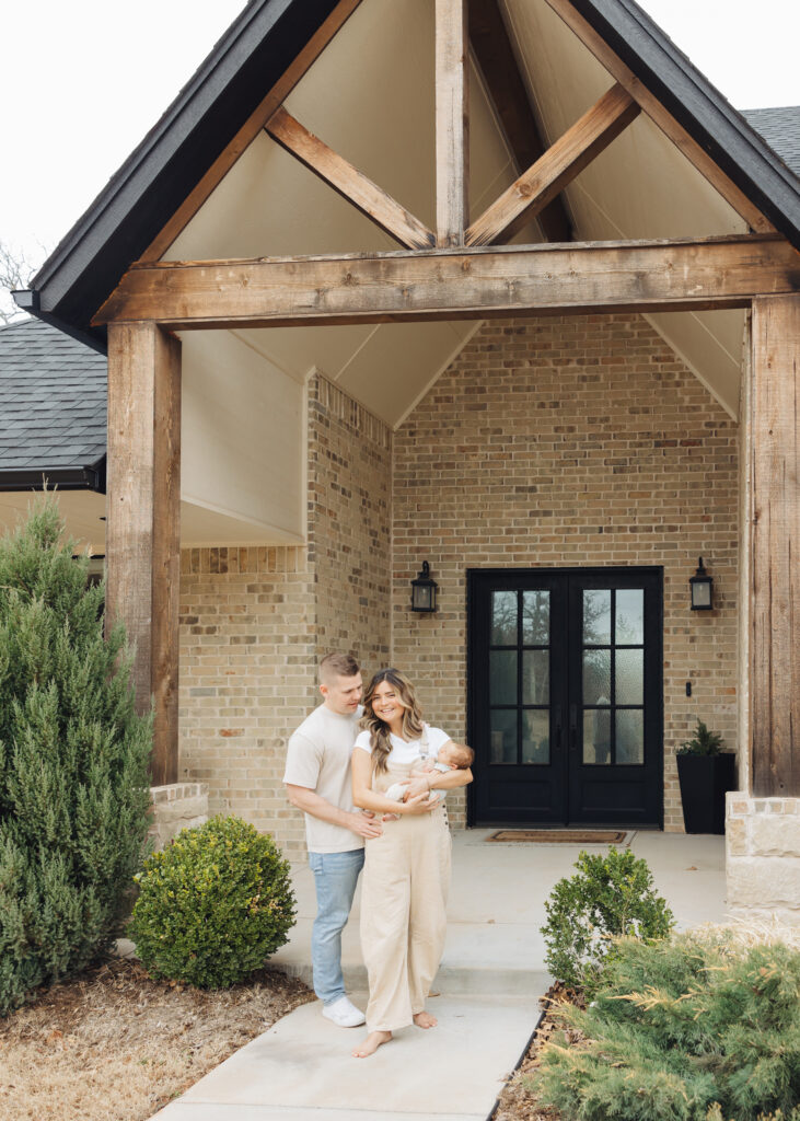 Standing in front of the house showing off their love, taken by Edmond Lifestyle Newborn Photographer Bailey Griffith Photography